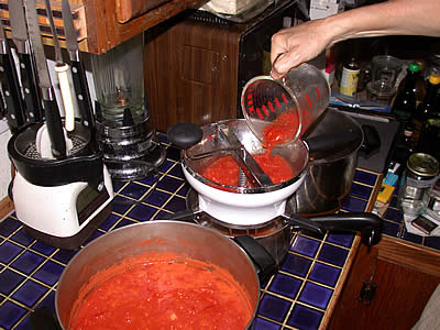 Pouring cooked tomatoes into the food mill